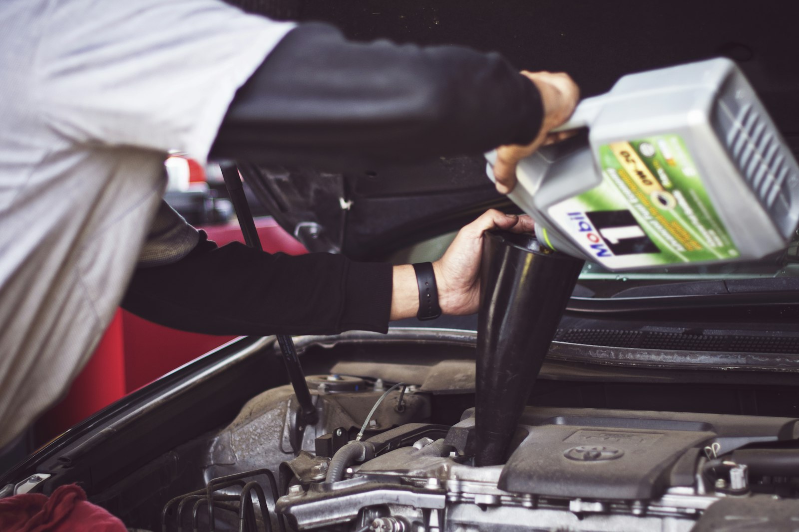 Technician inspecting an open engine bay in a workshop